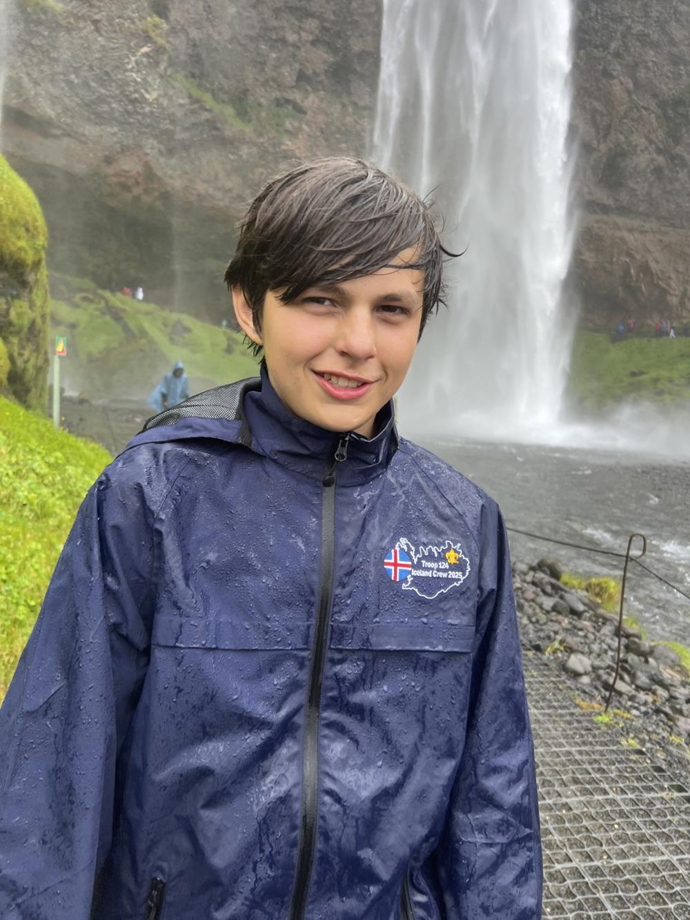 Customer photo from Kim of our Traverse Waterproof Jacket - Men's - Embroidered, a boy standing in front of a waterfall