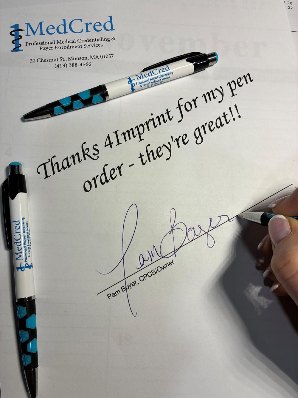 Customer photo from Pam of our Mardi Gras Hex Pen, a hand writing on a paper with a pen and a few pens