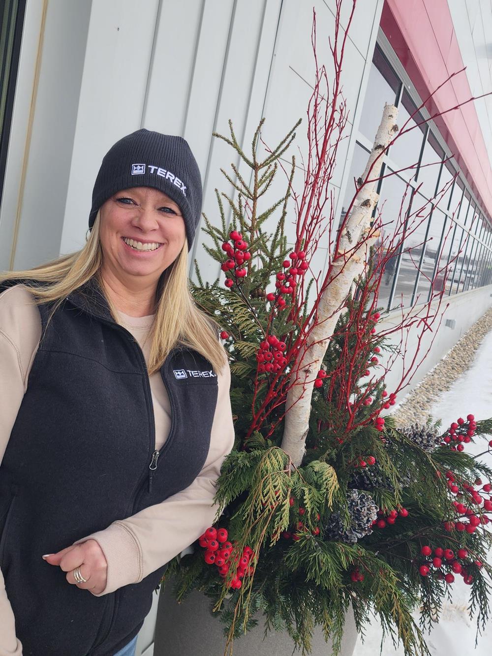 Customer photo from Debi of our New Era Fleece Lined Beanie, a woman smiling next to a plant