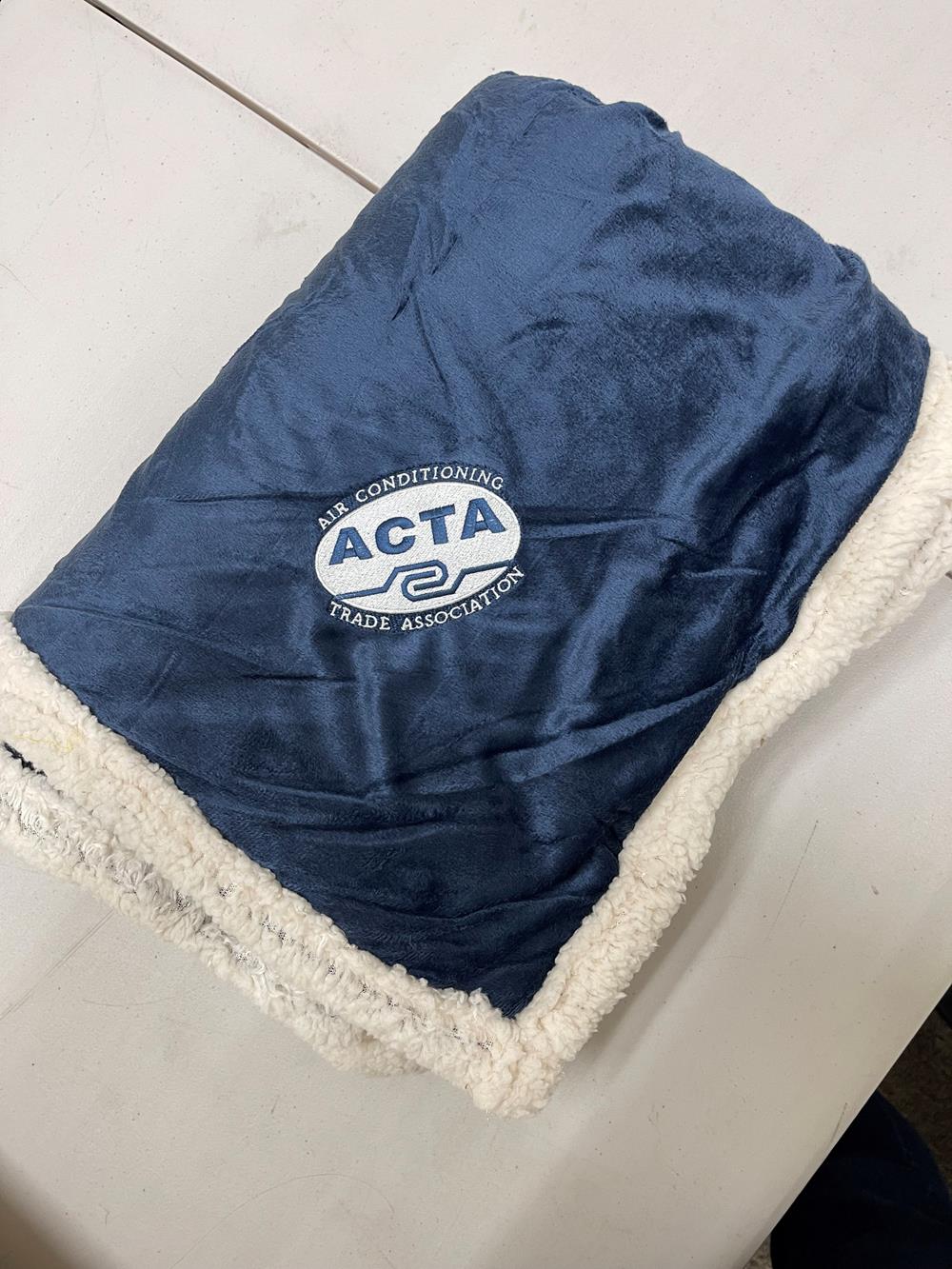 Customer photo from Becky of our Field & Co. Sherpa Blanket, a blue blanket on a table