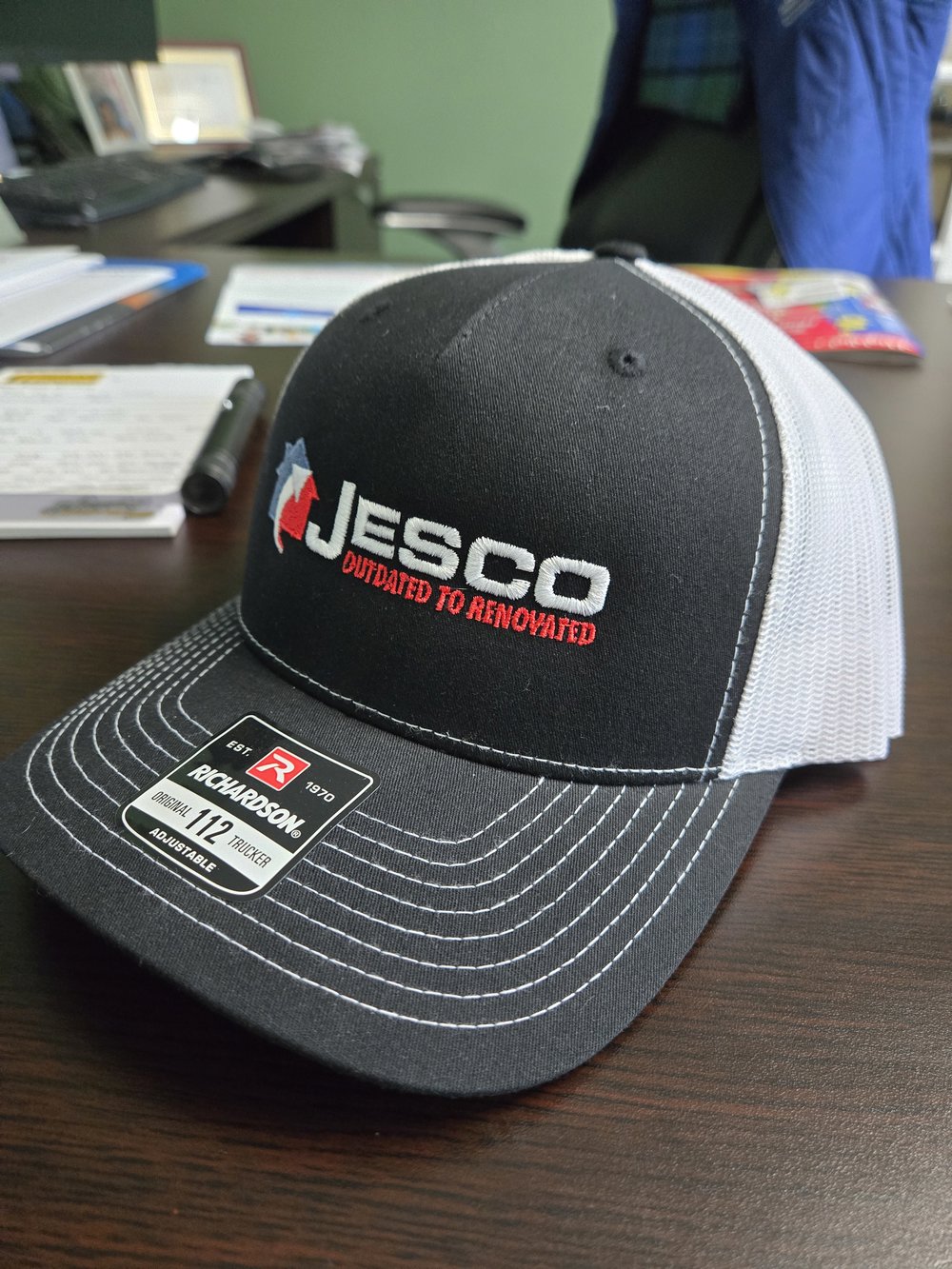 Customer photo from Chad of our Richardson Five Panel Snapback Trucker Cap, a black and white hat on a table