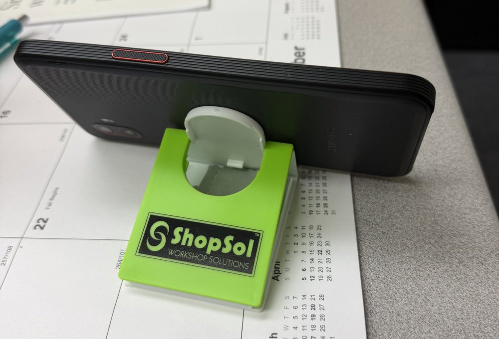 Customer photo from Adam of our Fold Flat Phone Stand with Microfiber Cloth, a cell phone on a calendar
