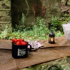 Customer photo from Ryan of our Campfire Ceramic Mug - Colors - 15 oz, a champagne bottle in ice bucket and a mug of strawberries