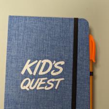 a blue notebook with white text and orange pen