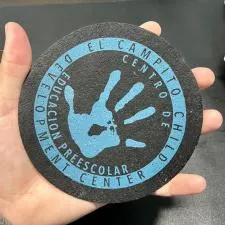 Customer photo from Aleyna of our Re-Tire Jar Opener - 5" Circle, a hand holding a round black coaster with a blue handprint on it