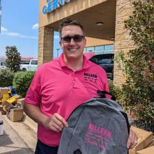 a man in a pink shirt holding a backpack in front of a building