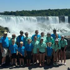 a group of people posing for a photo in front of a waterfall