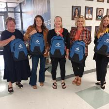 a group of women standing in a hallway with backpacks