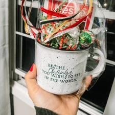 a hand holding a mug with a gift in it