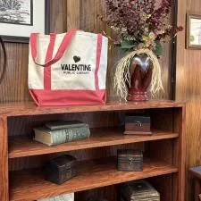 Customer photo from Carrie of our Two-Tone Accent Gusseted Tote Bag, a shelf with books and a bag on it