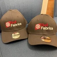 Customer photo from Ian of our New Era Structured Stretch Fit Cap - 3D Puff Embroidery, two hats on a chair