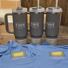 Customer photo from Charisse of our Stanley Quencher H2.0 FlowState Vacuum Mug with Straw - 30 oz., a group of grey and black shirts and a mug with logos on it