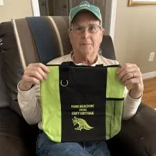 Customer photo from Ginger of our Fun Tote, a man sitting in a chair holding a bag