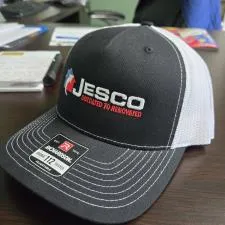 Customer photo from Chad of our Richardson Five Panel Snapback Trucker Cap, a black and white hat on a table