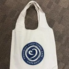 Customer photo from Jenny of our Take Home 5-oz Cotton Shopper Tote - 24 hr, a white bag with a blue circle on it