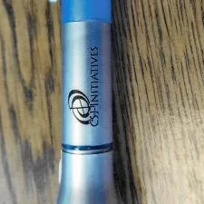 Customer photo from Katrina of our Flashlight with Pen and Lanyard, a blue pen on a wood surface